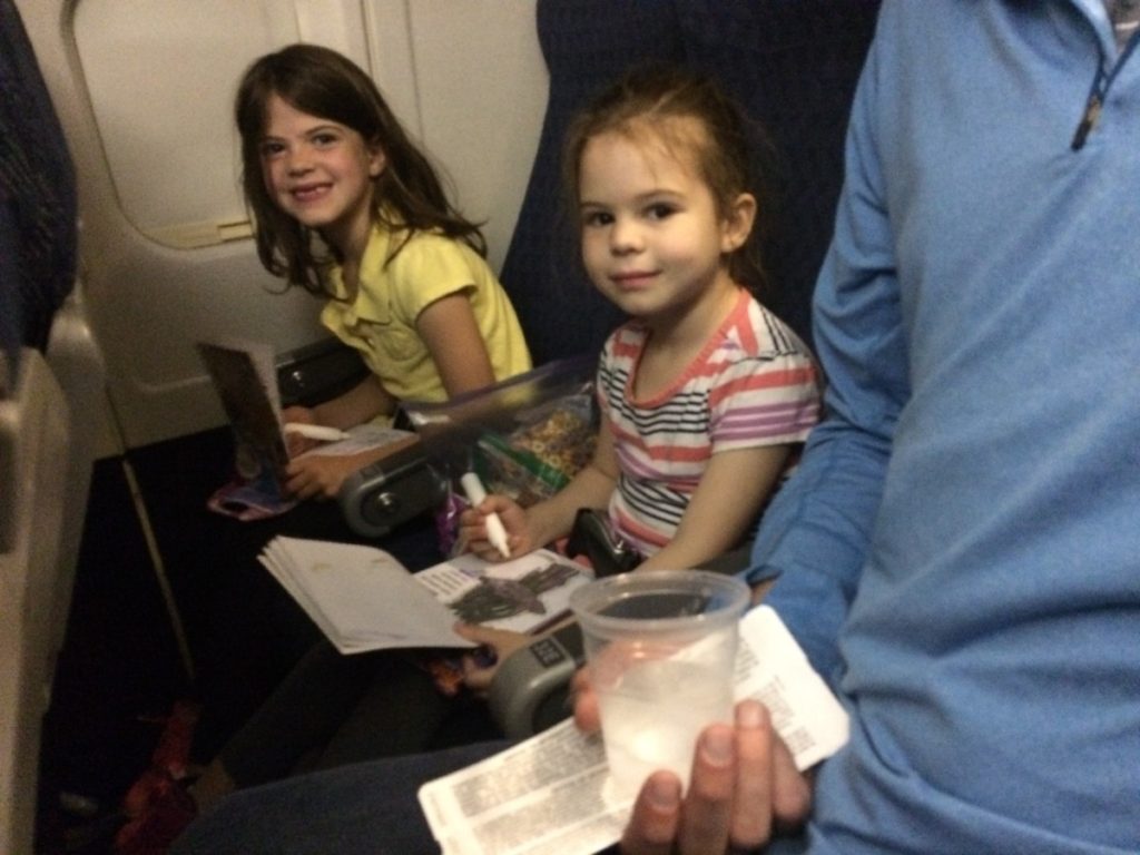 2 girls color on activity pads on the airplane