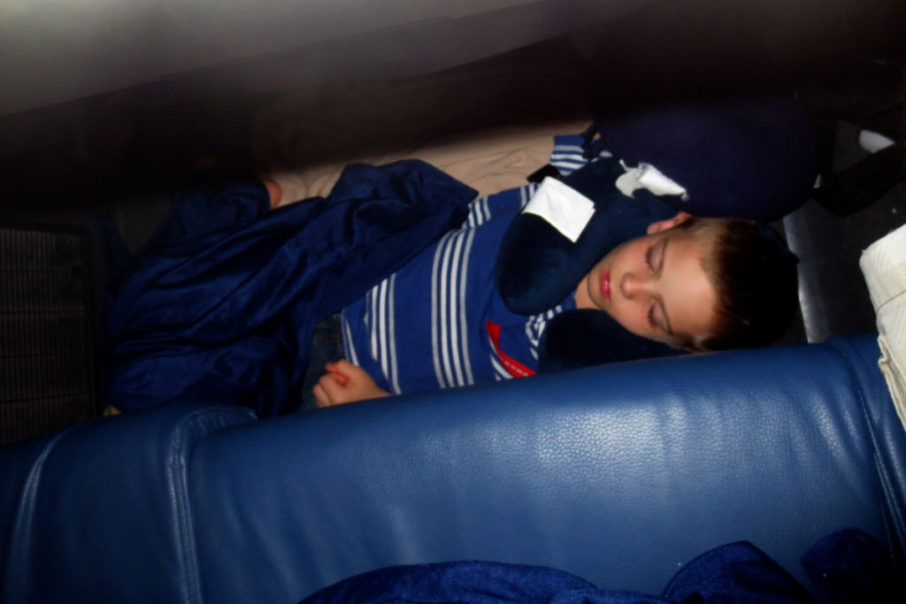 A boy sleeps on the floor of the airplane