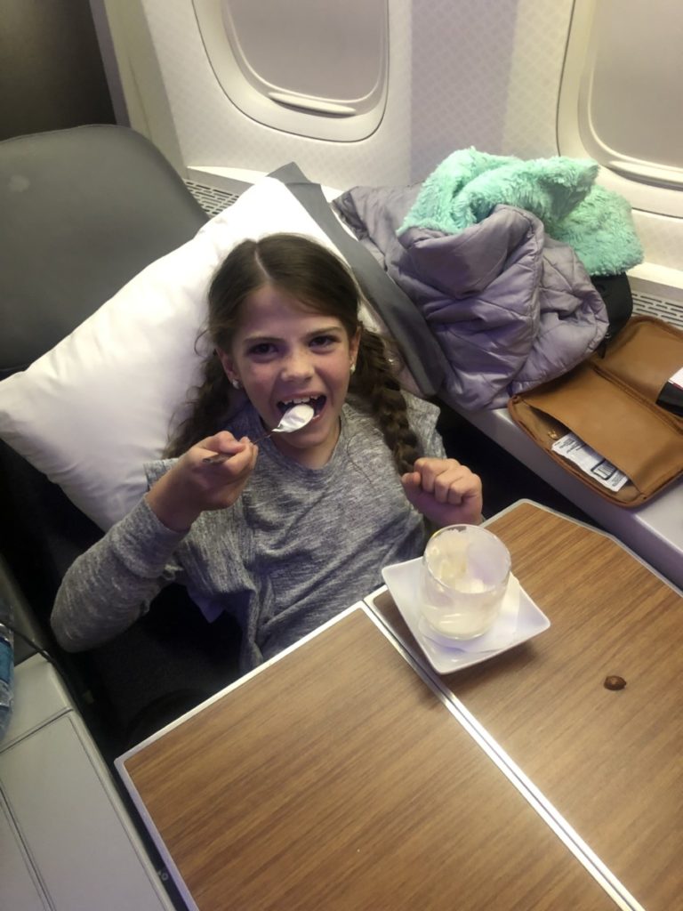 a girl eats a treat sitting in first class on an airplane