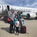 Family of 6 stand on the tarmac in front of an American Eagle plane