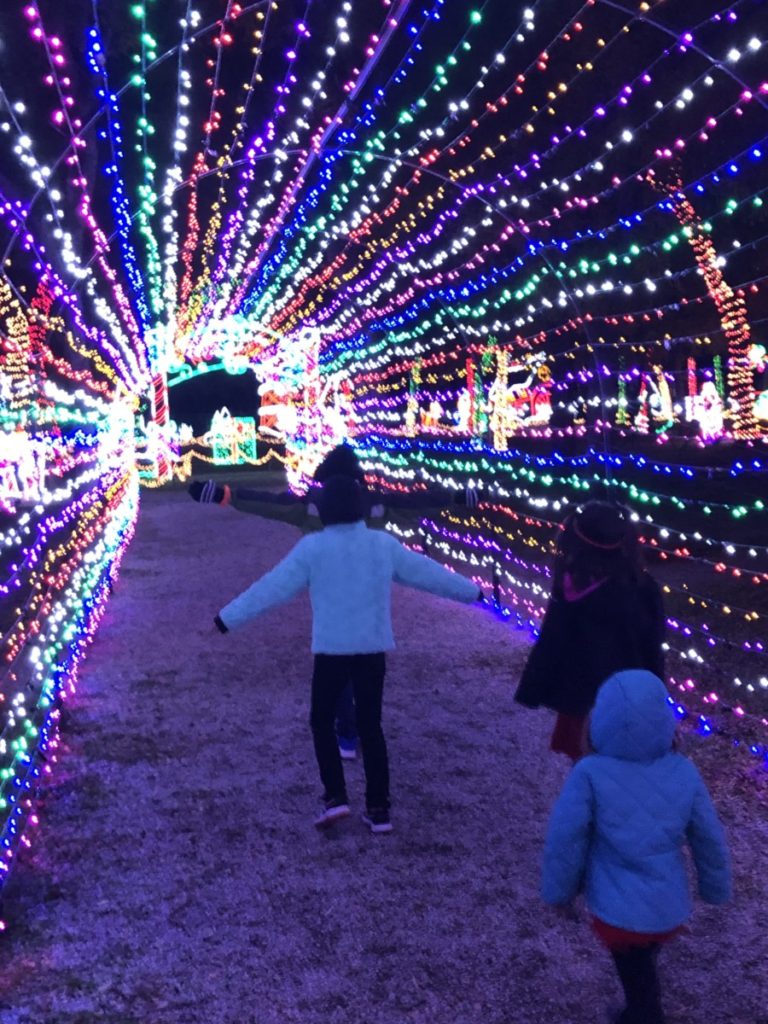4 kids run through a lighted tunnel at Prairie Lights in Grand Prairie, Texas