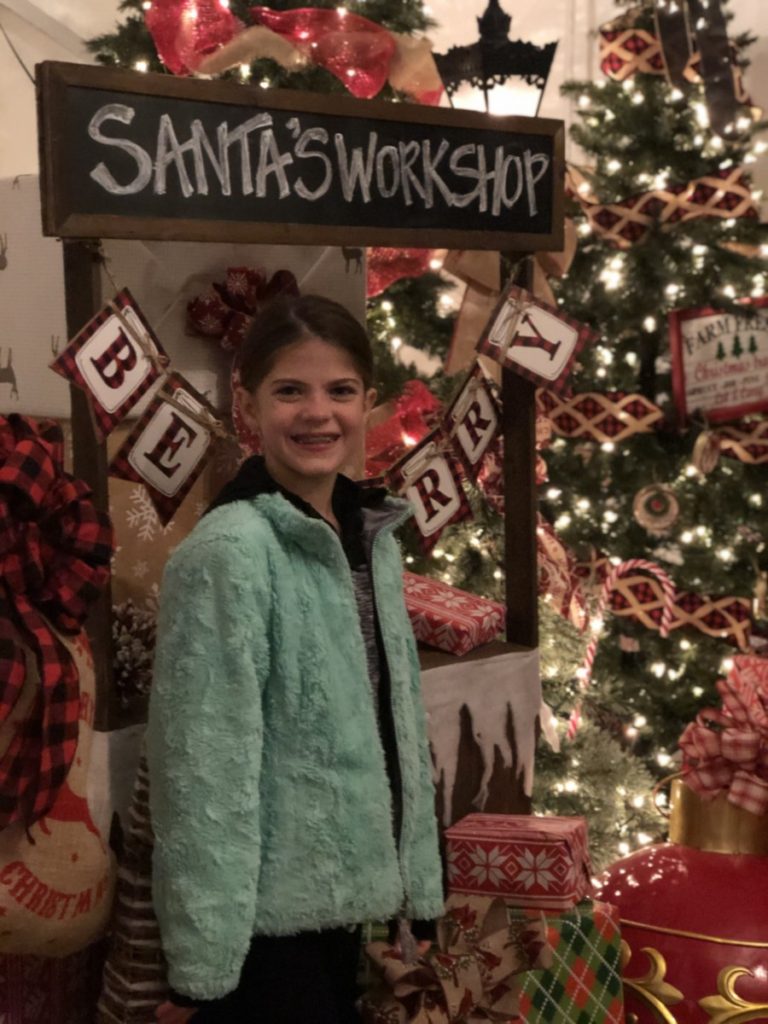 A girl in front of Santa's workshop sign at Prairie Lights in Grand Prairie