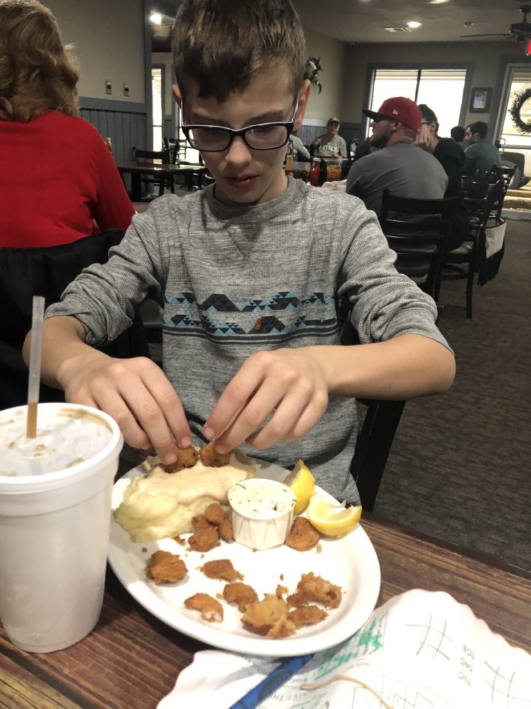 a boy eats Popcorn Shrimpt at Vernon's Kuntry Katfish in Conroe Texas