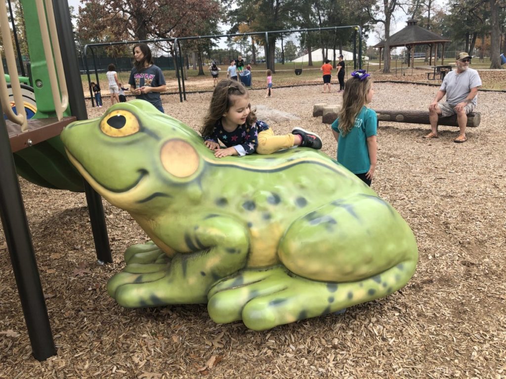 A toddler climbs a frog at Candy Cane Park in Conroe Texas