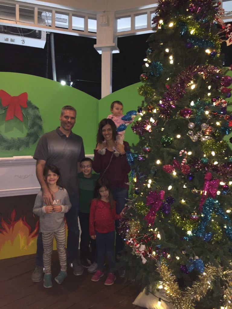 Family of 6 in next to a brightly decorated christmas tree