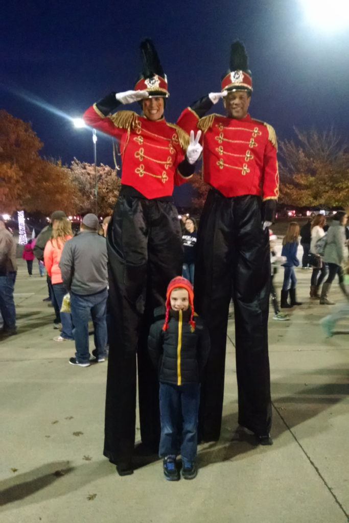 2 tall soldiers on stilts with a young boy