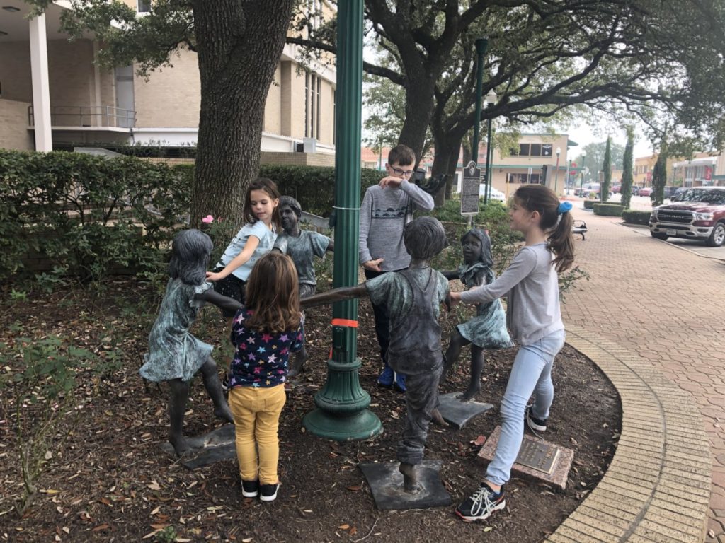 4 kids playing with a statue Ring-around-the Roses in Downtown Conroe, Texas