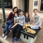 Mom and 4 kids sitting on a tiled Art bench in Downtown Conroe Texas