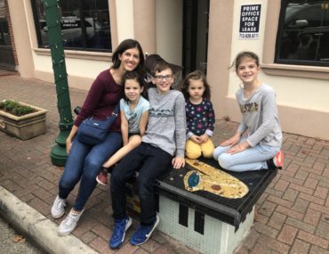 Mom and 4 kids sitting on a tiled Art bench in Downtown Conroe Texas