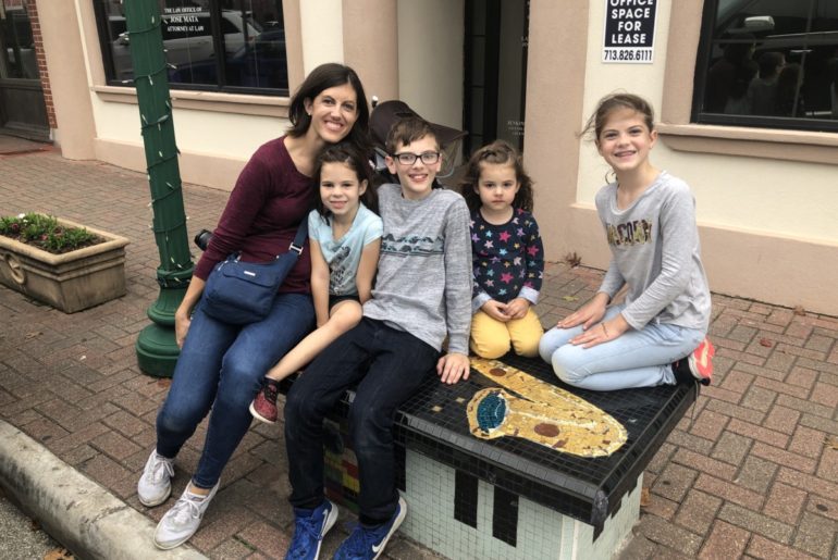 Mom and 4 kids sitting on a tiled Art bench in Downtown Conroe Texas