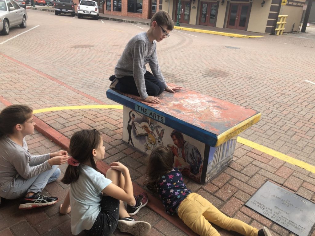 4 kids admire the ARTS bench in downtown Conroe