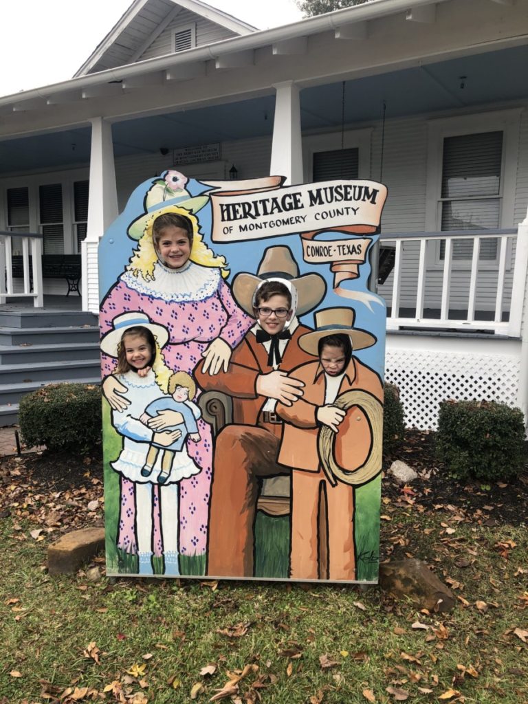 4 kids pose behind a photo opp at Heritage Museum of Montgomery County in Conroe Texas