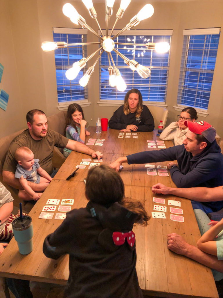 Adults and kids sit around the table playing a card game together at Texoma Luxury Rentals