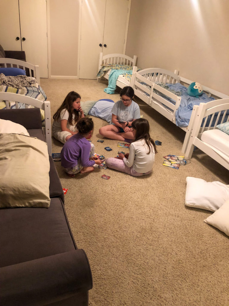 4 girls playing card games in room with 4 singles and 2 double beds at simply the best Texoma luxury Rental Property