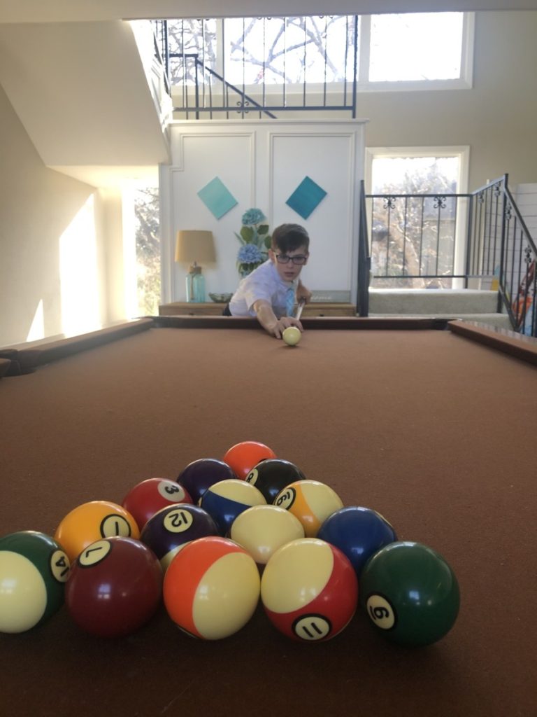 a young boy attempts to break the triangle playing pool at Simply the Best House at Texoma Luxury Rental Properties