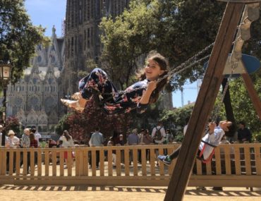 Young Girl swings in front of the Sagrada Familia in Barcelona, Spain