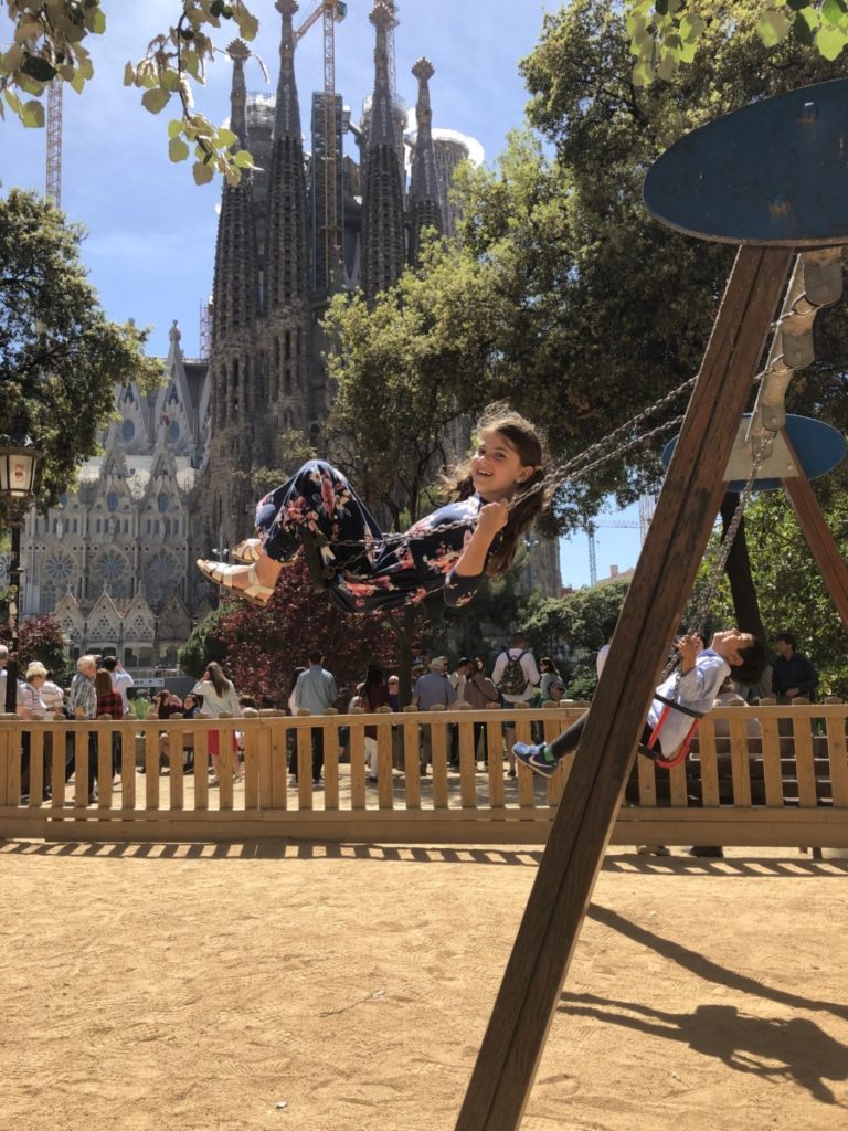 Young Girl swings in front of the Sagrada Familia in Barcelona, Spain