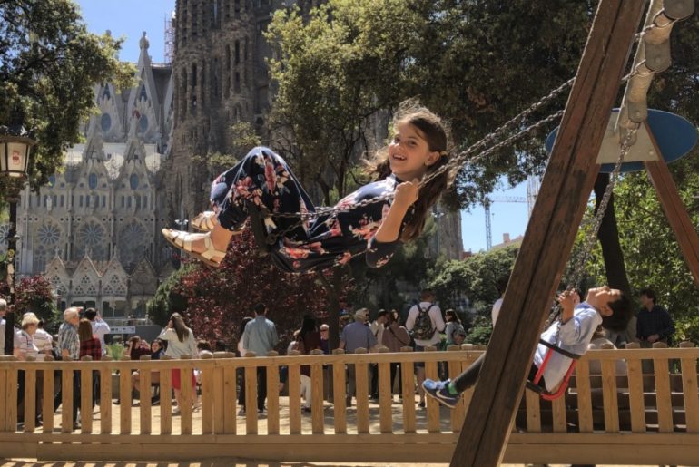 Young Girl swings in front of the Sagrada Familia in Barcelona, Spain
