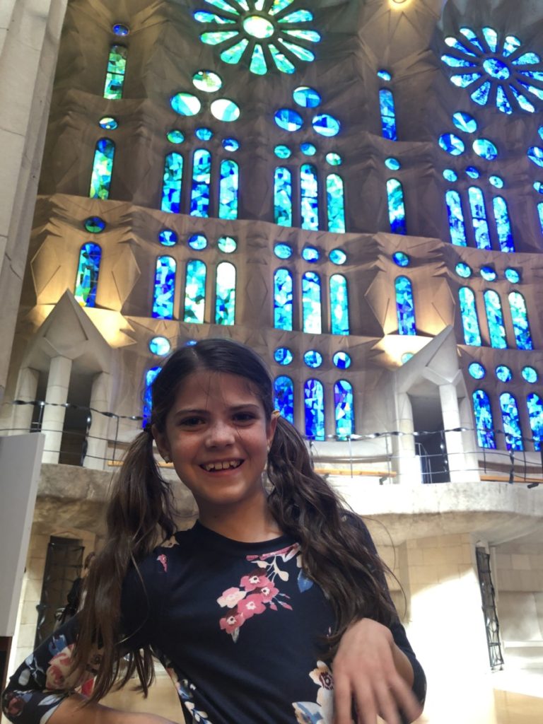 Young girl in front of blue and green stained glass at the sagrada Familia in Barcelona, Spain