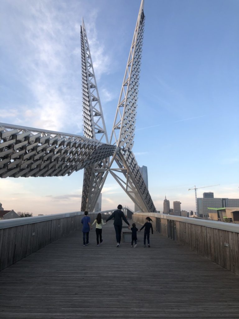Mom and 4 kids walk under the scissortail structure on a bridge in OKC