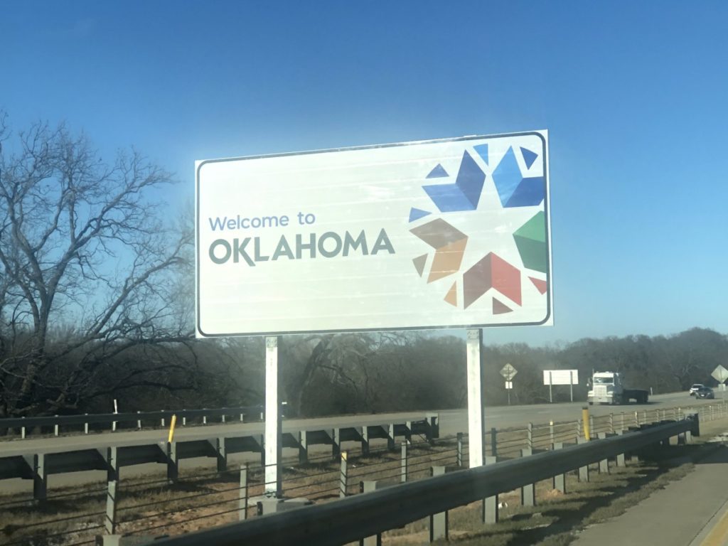 Going to Oklahoma with kids passing the road sign for Oklahoma state