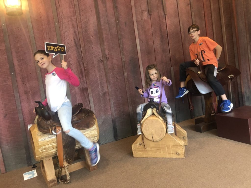 3 kids sit on saddles at the National Cowboy and Western museum in OKC