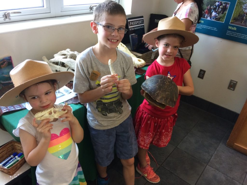 3 kids in Rangers hats holding turtle shells at the Everglades national Park Visitors Center