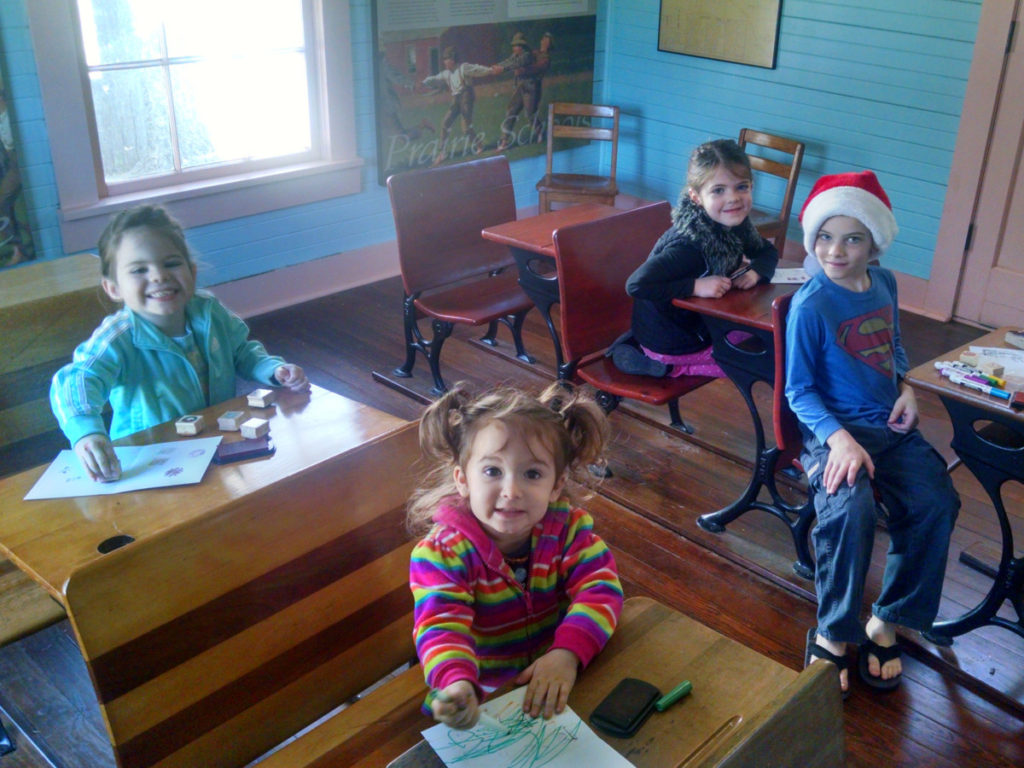 4 kids at the school house in Settlement-to-City Museum in Grapevine Texas
