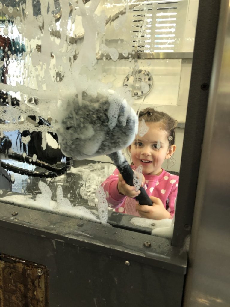 Toddler washes the window of a car at Children's Museum in Minnesota