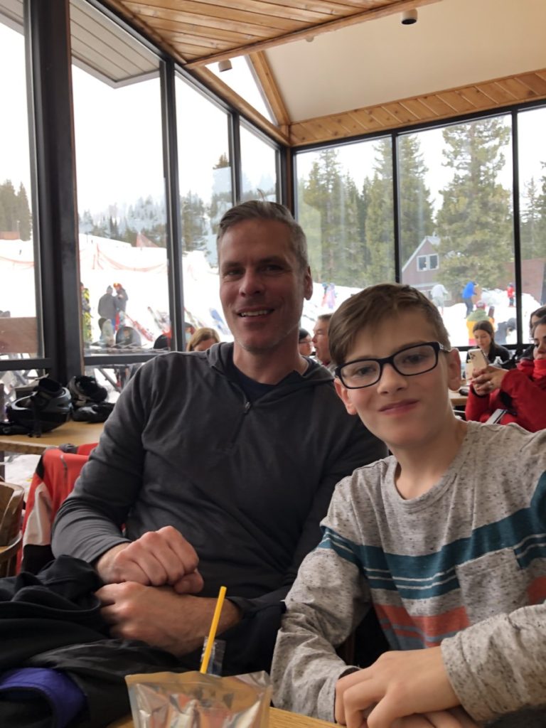 dad and son enjoy lunch at the Brighton Ski resort Lodge with a view of the slopes