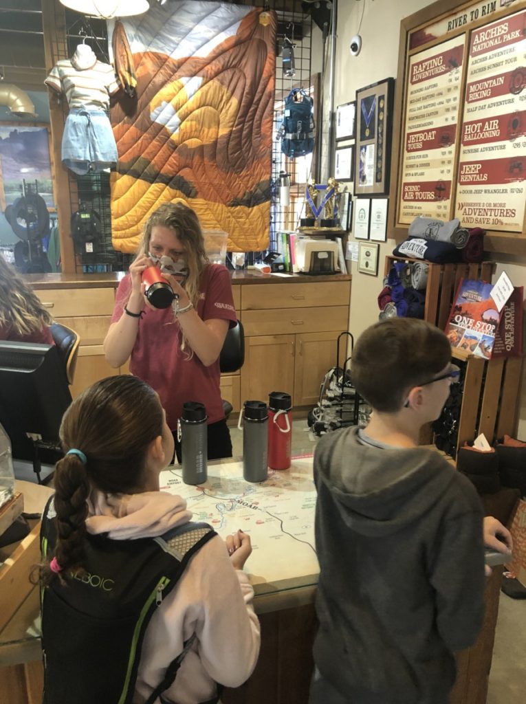 2 kids receive Hydroflask "Moab" water bottles from workers in the Moab Adventure Center before a Hummer tour