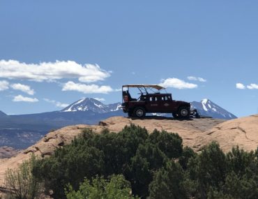 Hummer park on redrock with snowcapped mountains in the distance