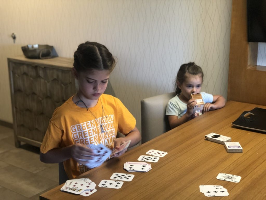 A girl plays cards in Hyatt Place Living room casita in Moab