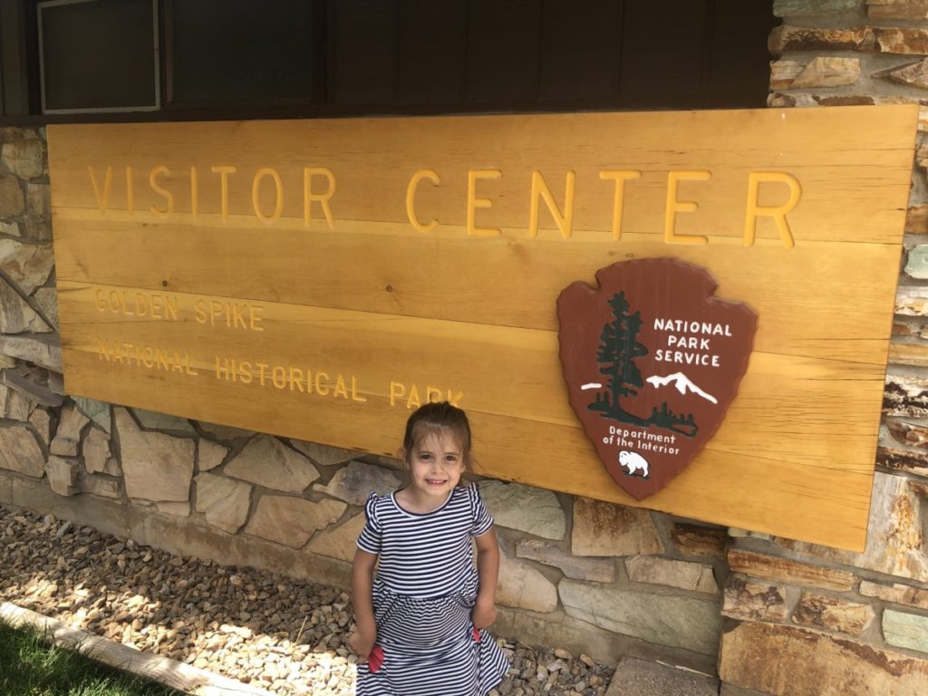 A toddler stands at the Golden Spike Visitor's Center Sign