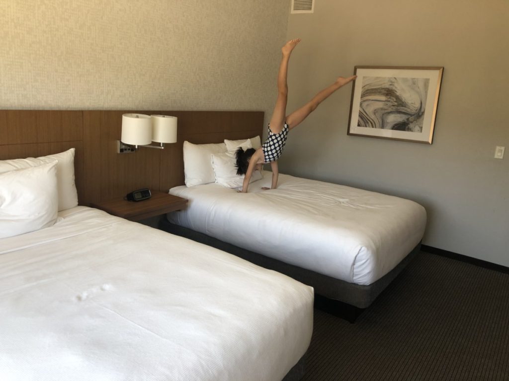 A girl does a hand stand on the bed at Hyatt Place in Moab