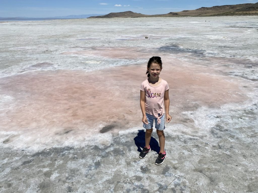 A girl stands next to a pink salt pond at the Great Salt Lake