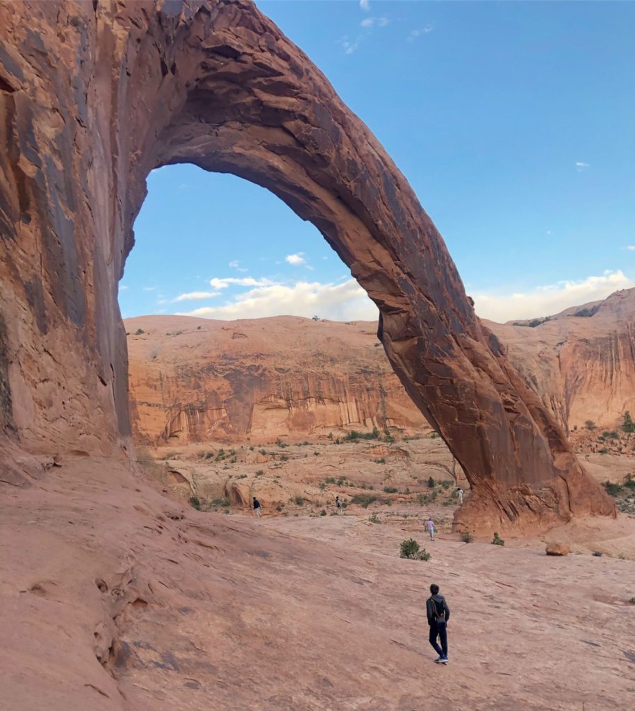 Boy walks toward Corona Arch near Arches National Park and Moab