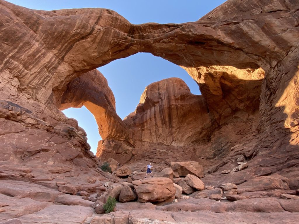 Boy stands under Double Arch in Arches National Park