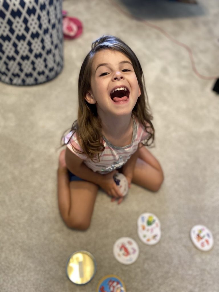 A little girls smiles big while playing spot it junior family games