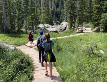 4 kids walk on a boardwalk through a field to Emerald Lake in Rocky Mountain National Park