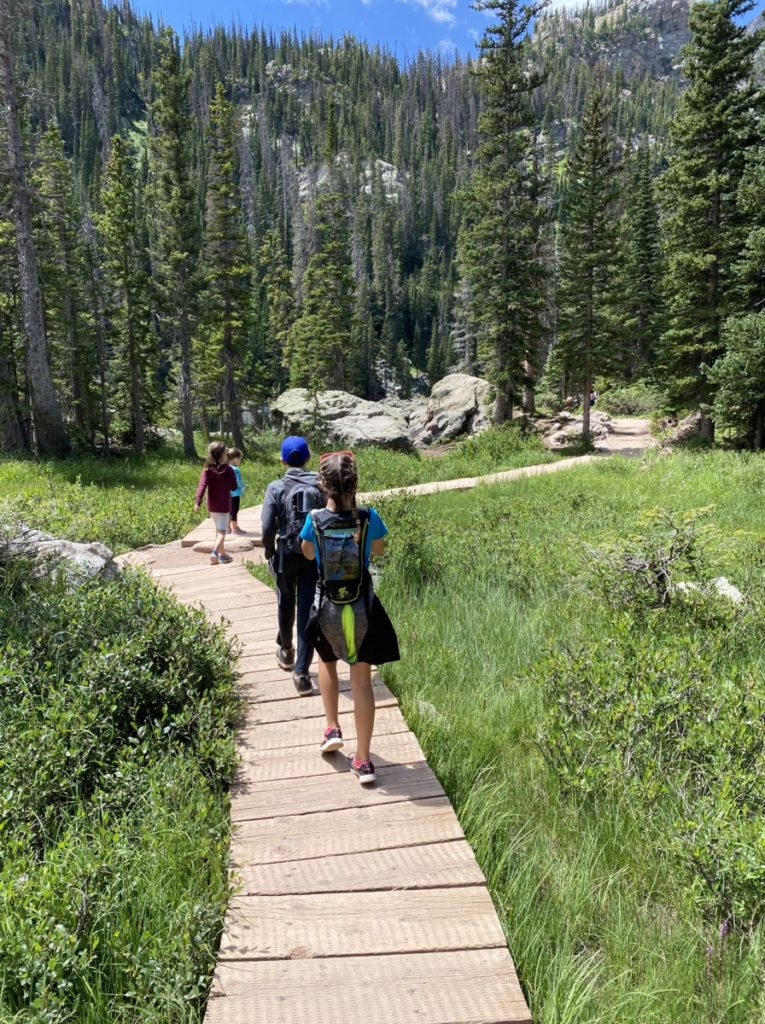 4 kids walk on a boardwalk through a field to Emerald Lake in Rocky Mountain National Park