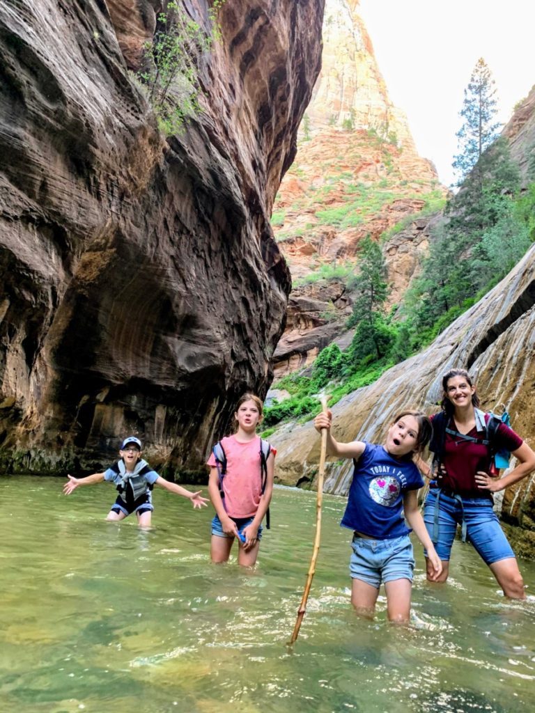 mom and 3 kids hiking the narrows in Water to their knees