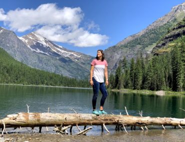 A woman looks at the mountain peaks over avalanche lake in Glacier National Park