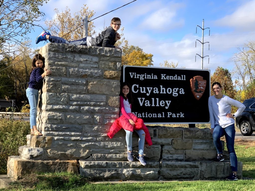 Cuyahoga Valley NAtional Park sign at the park entrance with 4 kids smiling kids 