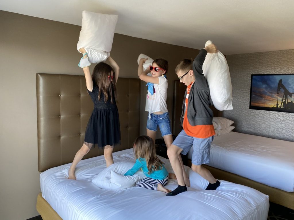 4 kids have a pillow fight on the beds in Drury Inn and Suites