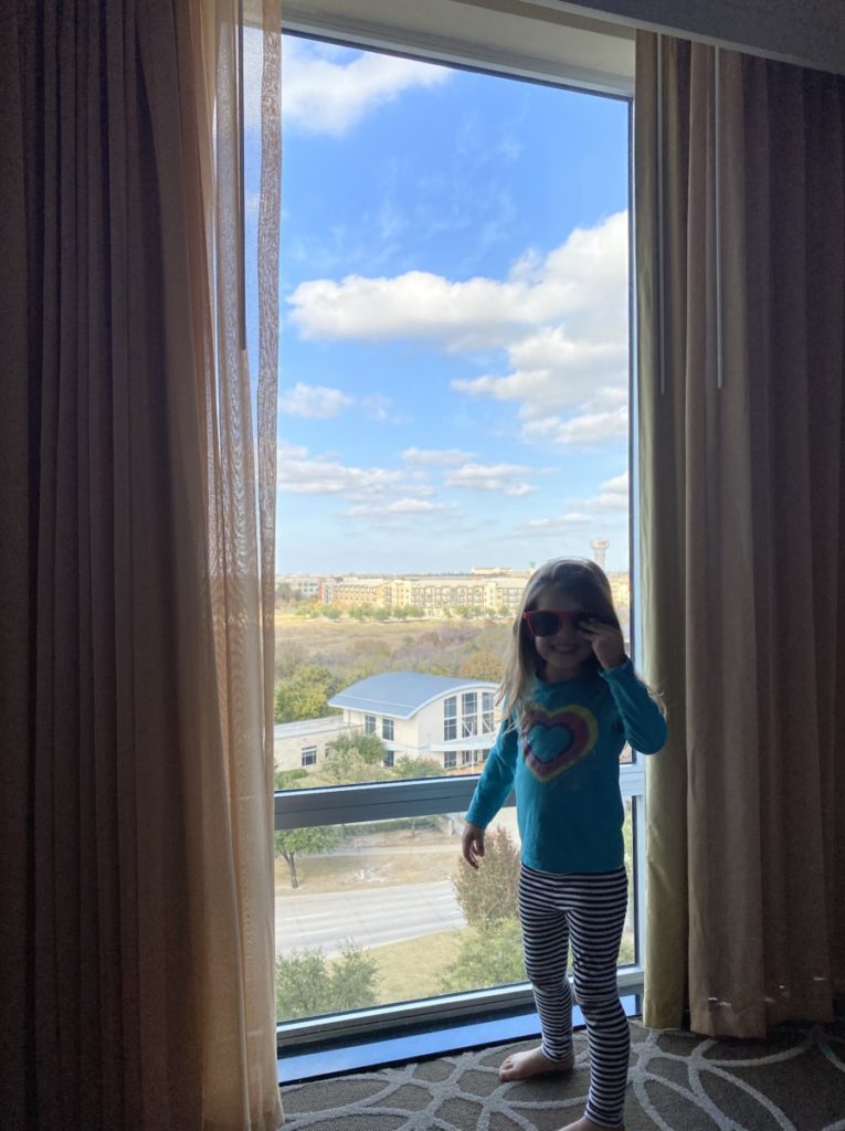 A young girl with sunglasses looks over the Eigth Floor View of the Drury Inn and Suites in Frisco