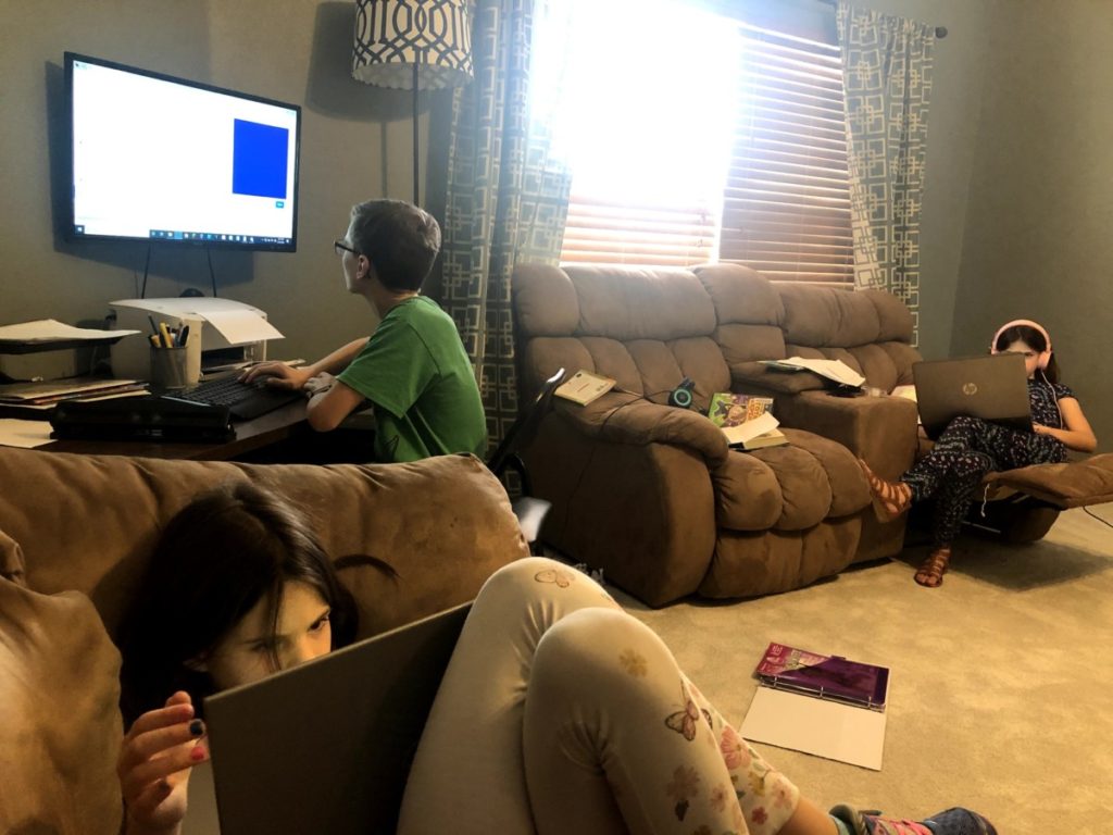 3 kids laying on couches trying to complete virtual schoool during the pandemic stay-at-home orders