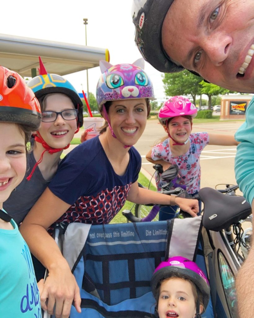 Family of 6 with helmets on a bike ride