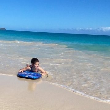 A young girl boogie boards on Lanikai beach on Oahu, Hawaii