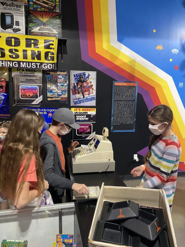 3 kids play cashier at the NAtional Video Games museum, what to do in Frisco with kids